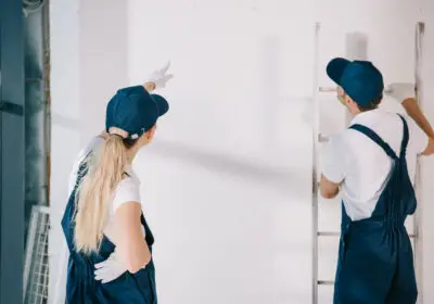 13-stock-photo-young-painter-uniform-pointing-finger-white-wall-while-standing-coworker