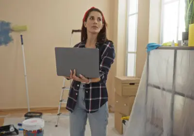 22-stock-photo-woman-holding-laptop-living-room-home-renovation-painting-supplies-ladder